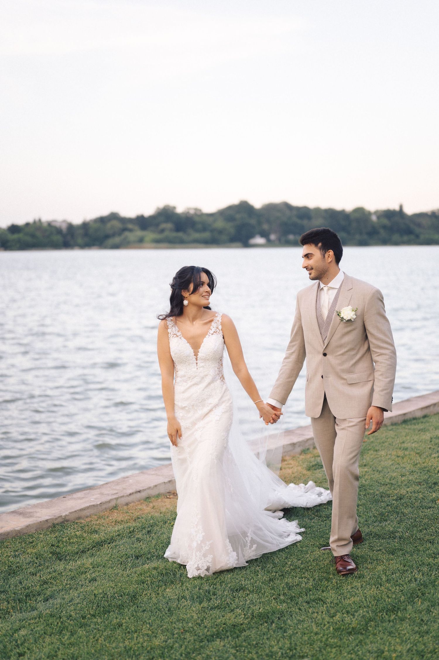 A romantic waterfront photoshoot at sunset with a couple by the lakeside in elegant formal attire.