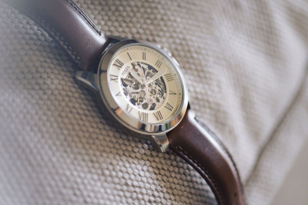 A classic silver wristwatch with Roman numerals and a brown leather band shown from multiple angles in detail.