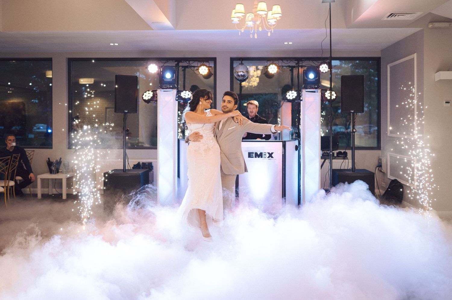 Two dancers perform a romantic first dance on a misty dancefloor with sparkling lights and smoke effects at an elegant venue.