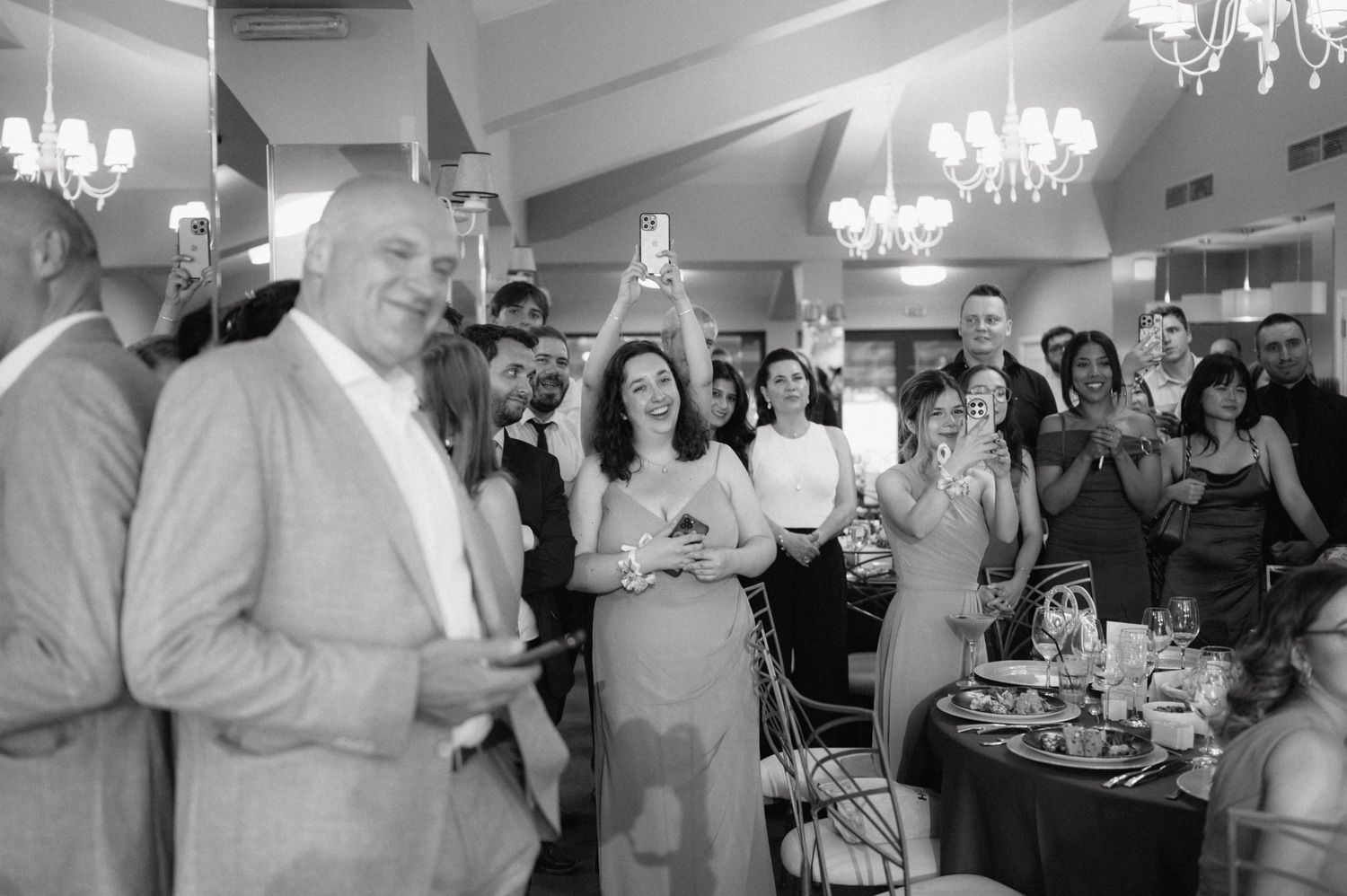 Wedding guests dancing in an elegant banquet hall with crystal chandeliers and a festive celebration atmosphere.
