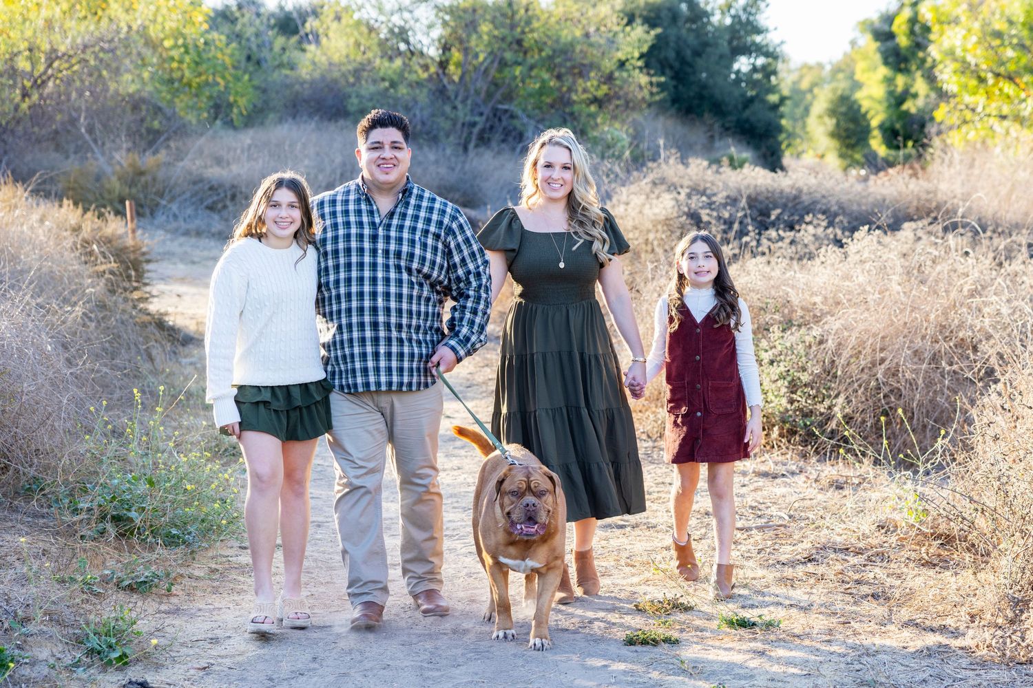 Irvine Park photographer captures Family of four with two daughters and their dog walk together on a scenic nature trail.