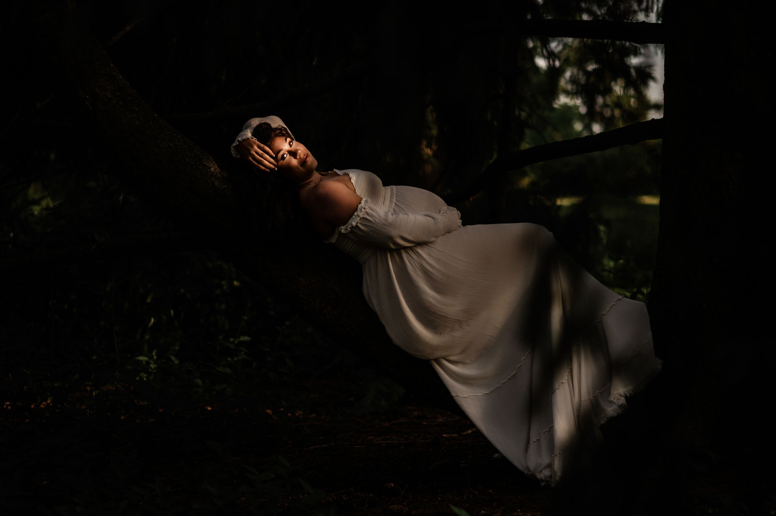 A person in a flowing gray dress levitates gracefully in a dark forest setting with dramatic lighting.