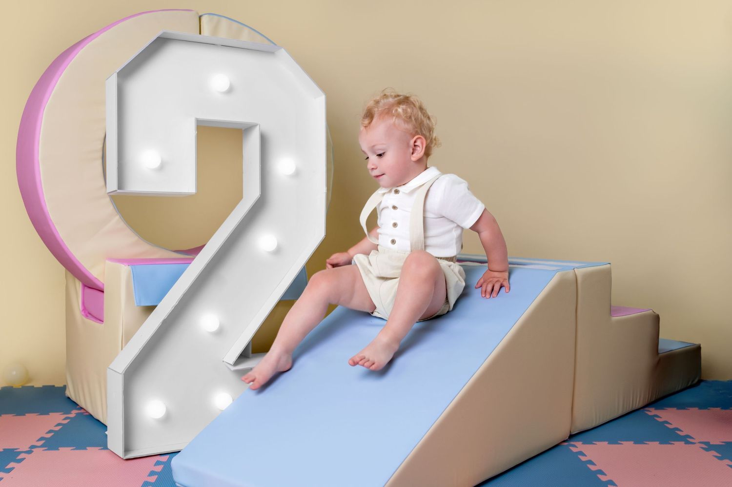 Two-year-old playing with soft play slide during milestone photoshoot near Saffron Walden, Essex.