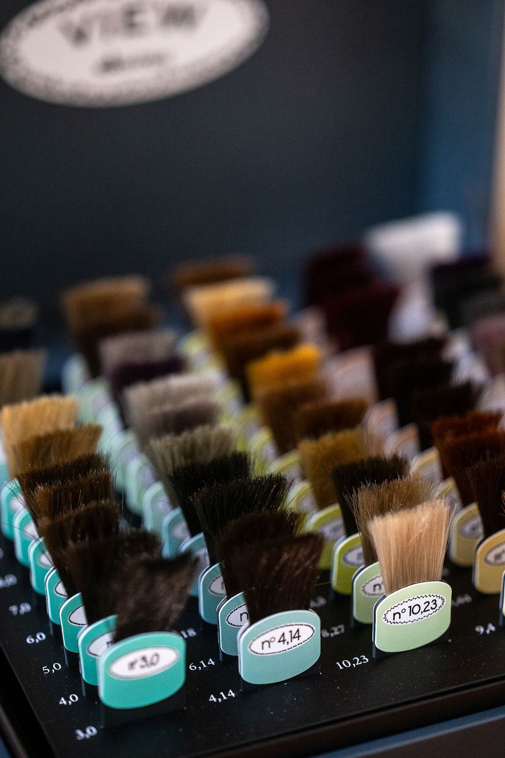 An organized set of professional hairbrushes arranged in rows on a dark salon counter display.