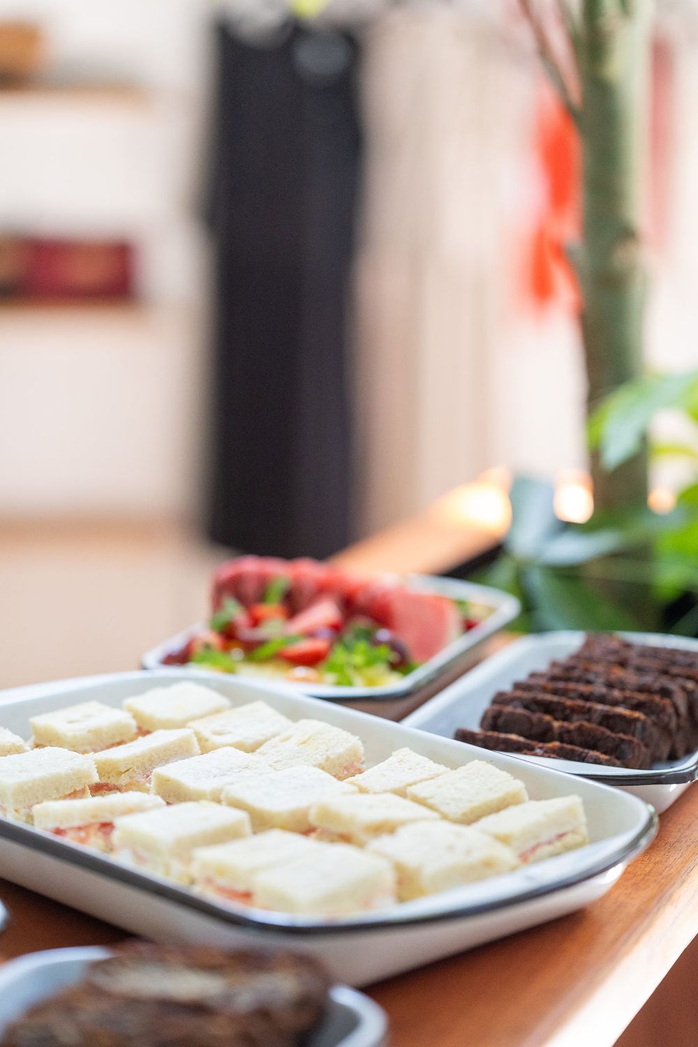 White frosted brownies topped with red sprinkles displayed in diagonal rows on rectangular plates.