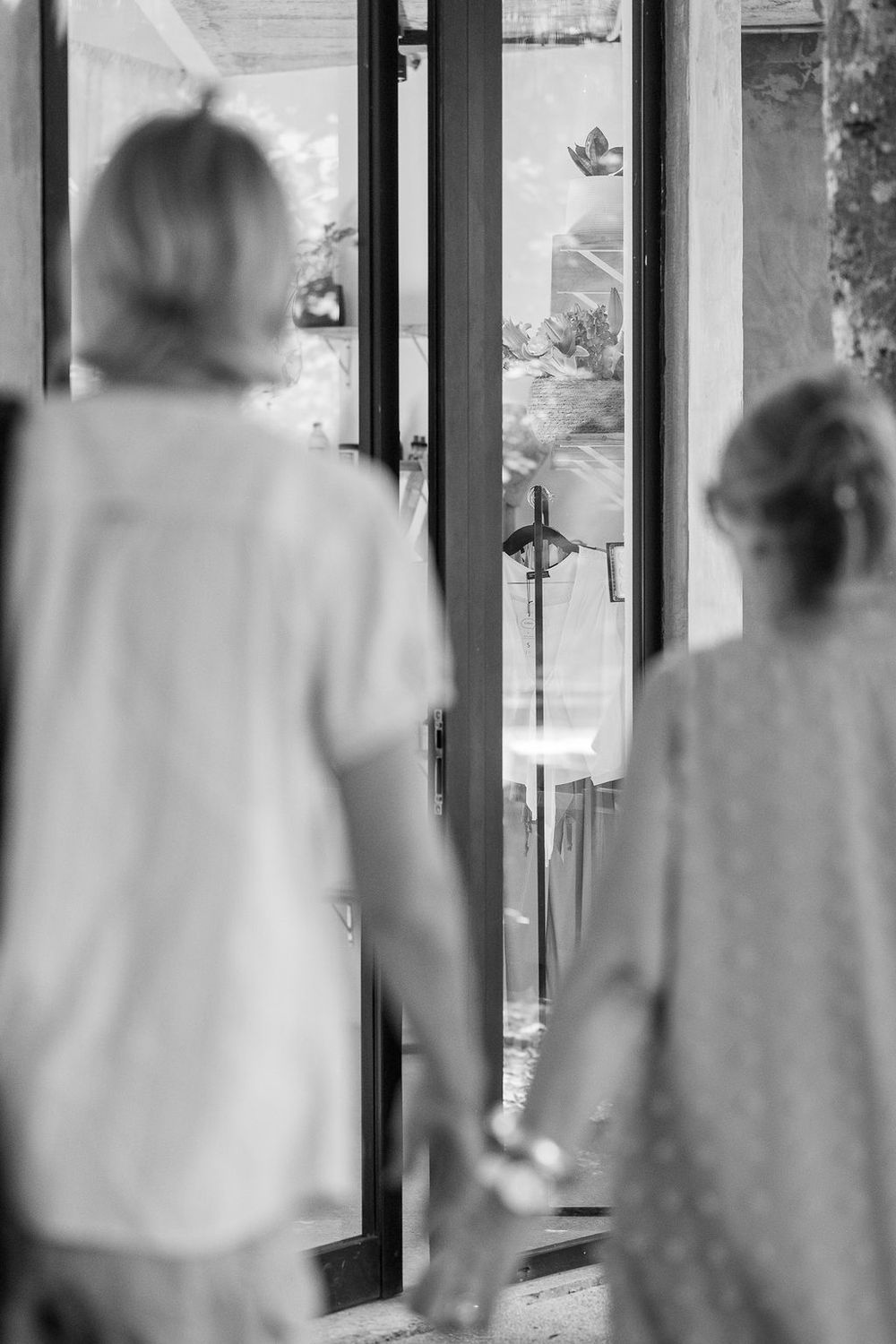 Two silhouettes stand backlit in a doorway looking outward in black and white.