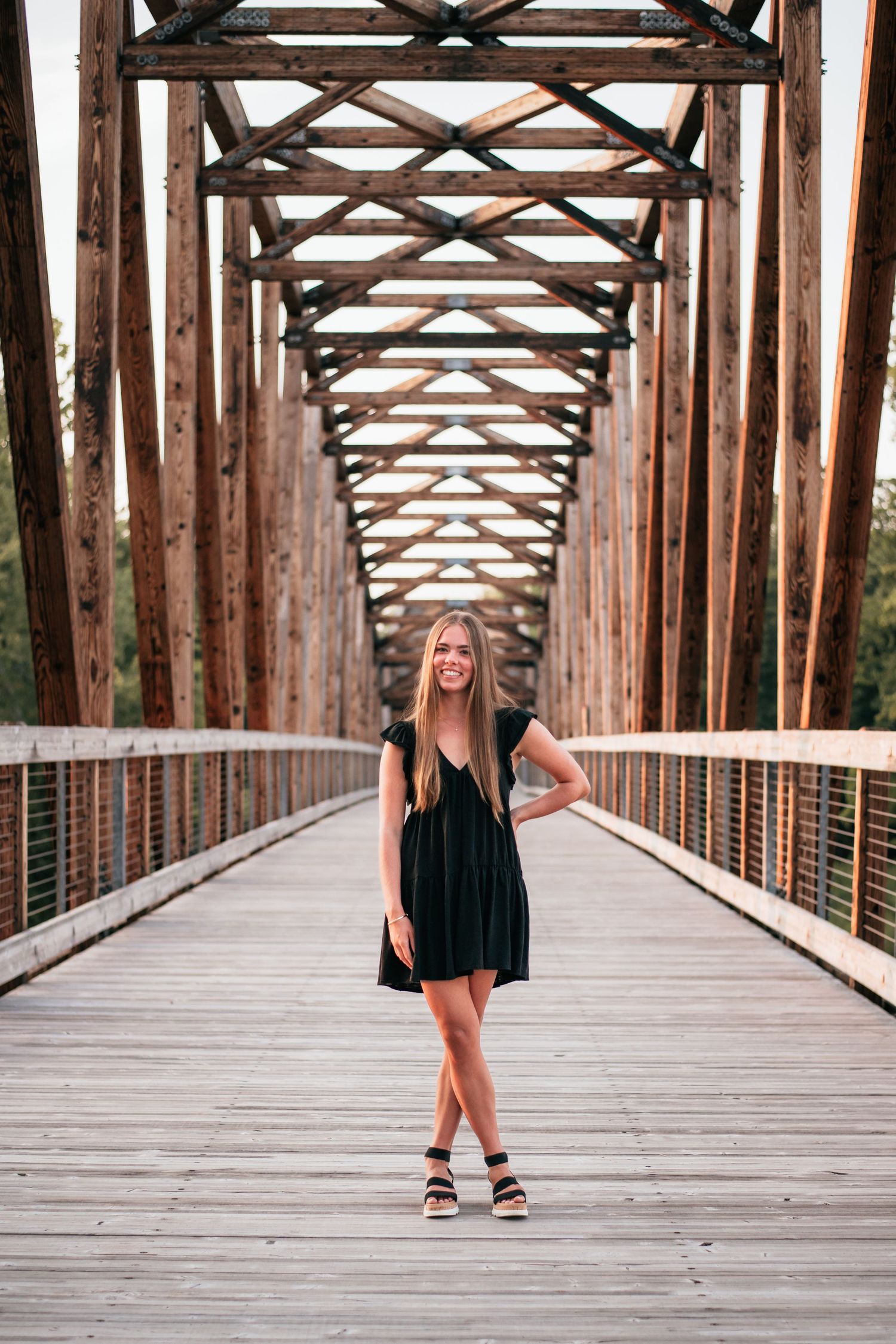 A senior girl posing during her senior session on an old wooden bridge.