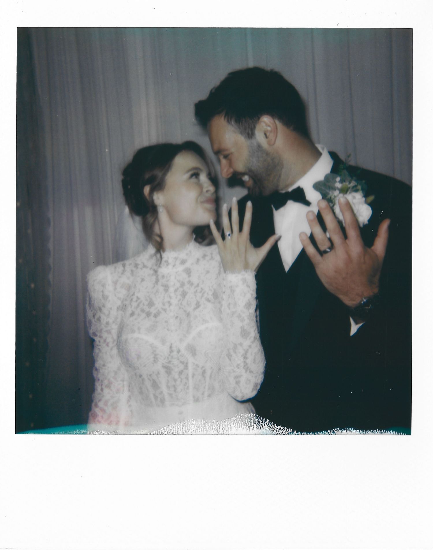A dreamy vintage-style polaroid photo captures a tender moment between a couple in elegant wedding attire.
