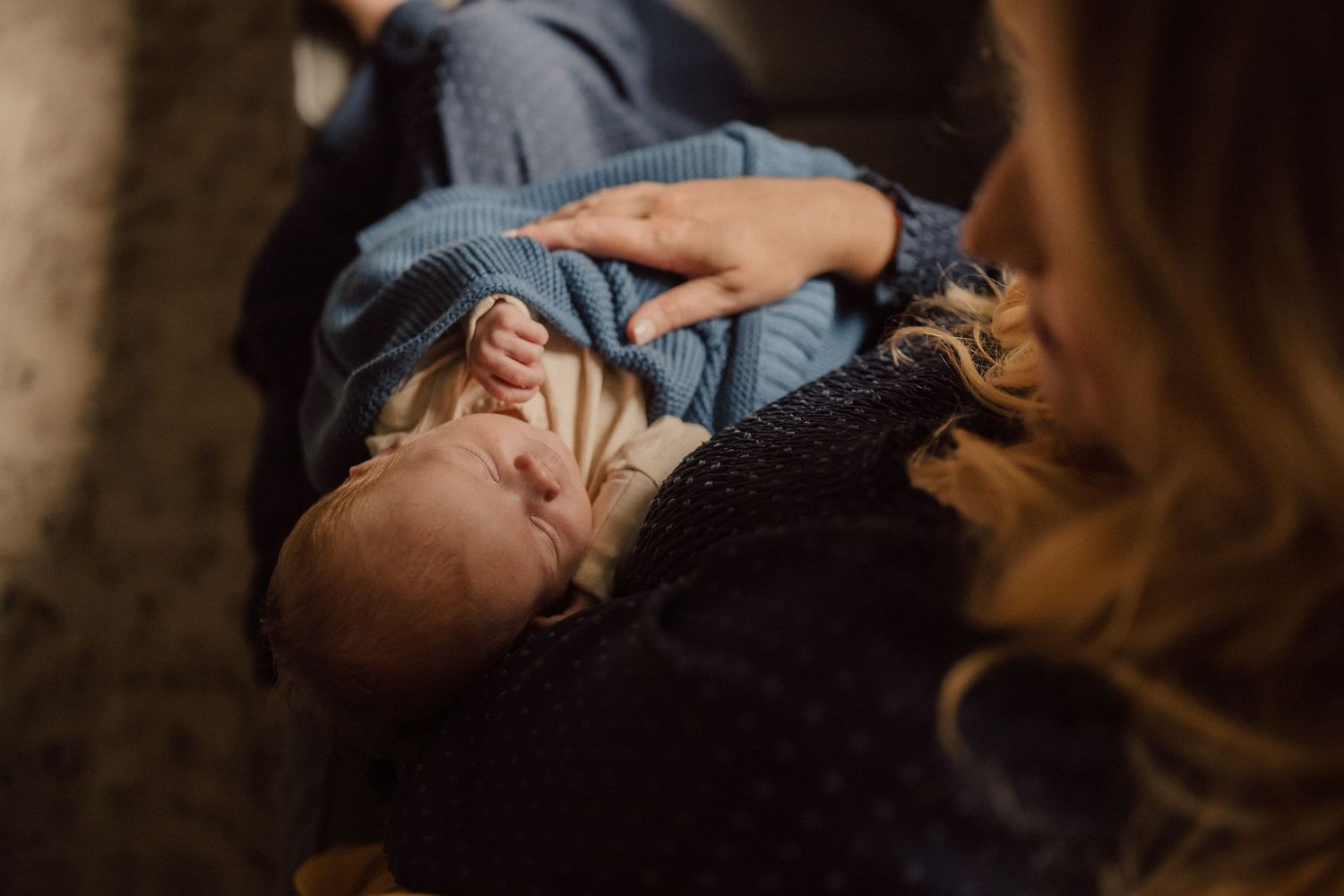 Close-up view of an infant resting peacefully on a dark blanket.