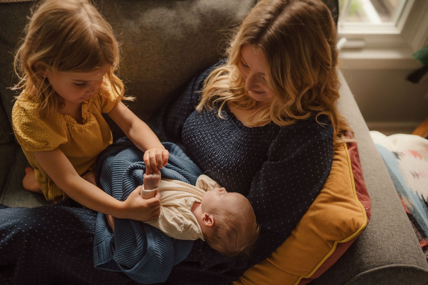 Gentle caregiving moments photographed in warm natural lighting on a comfortable couch.