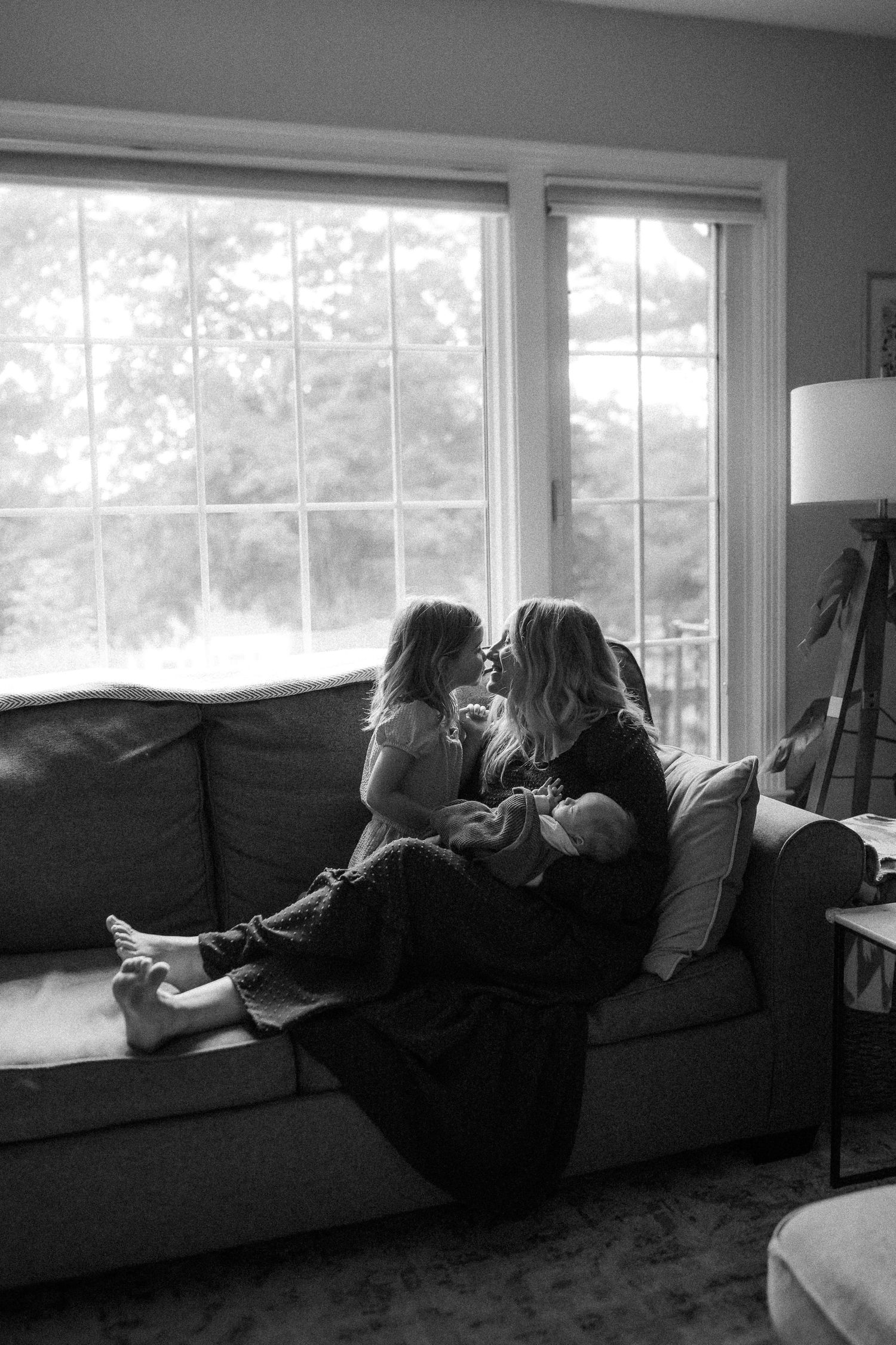 A black and white photo sequence showing someone lounging and reading on a couch by large windows.