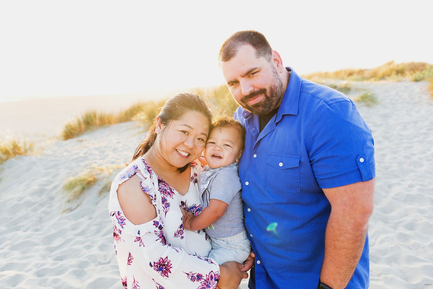 Family sharing joyful embrace on sandy beach during golden hour.