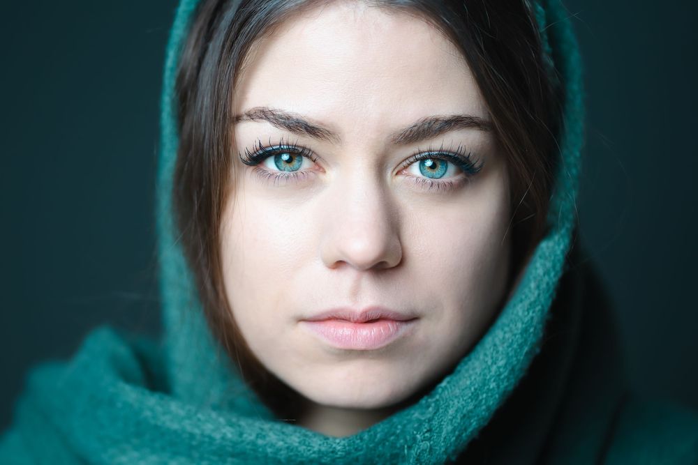 A series of dramatic close-up portraits showing intense blue eyes and a teal scarf against a dark background.