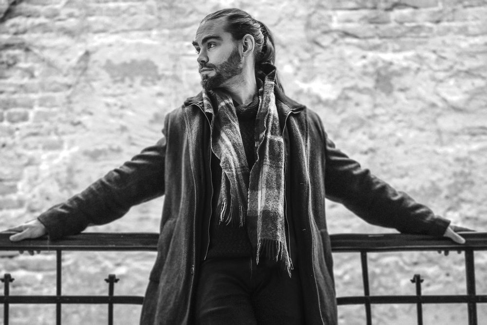 Two black and white profile images of someone leaning against railings with a stone wall backdrop.