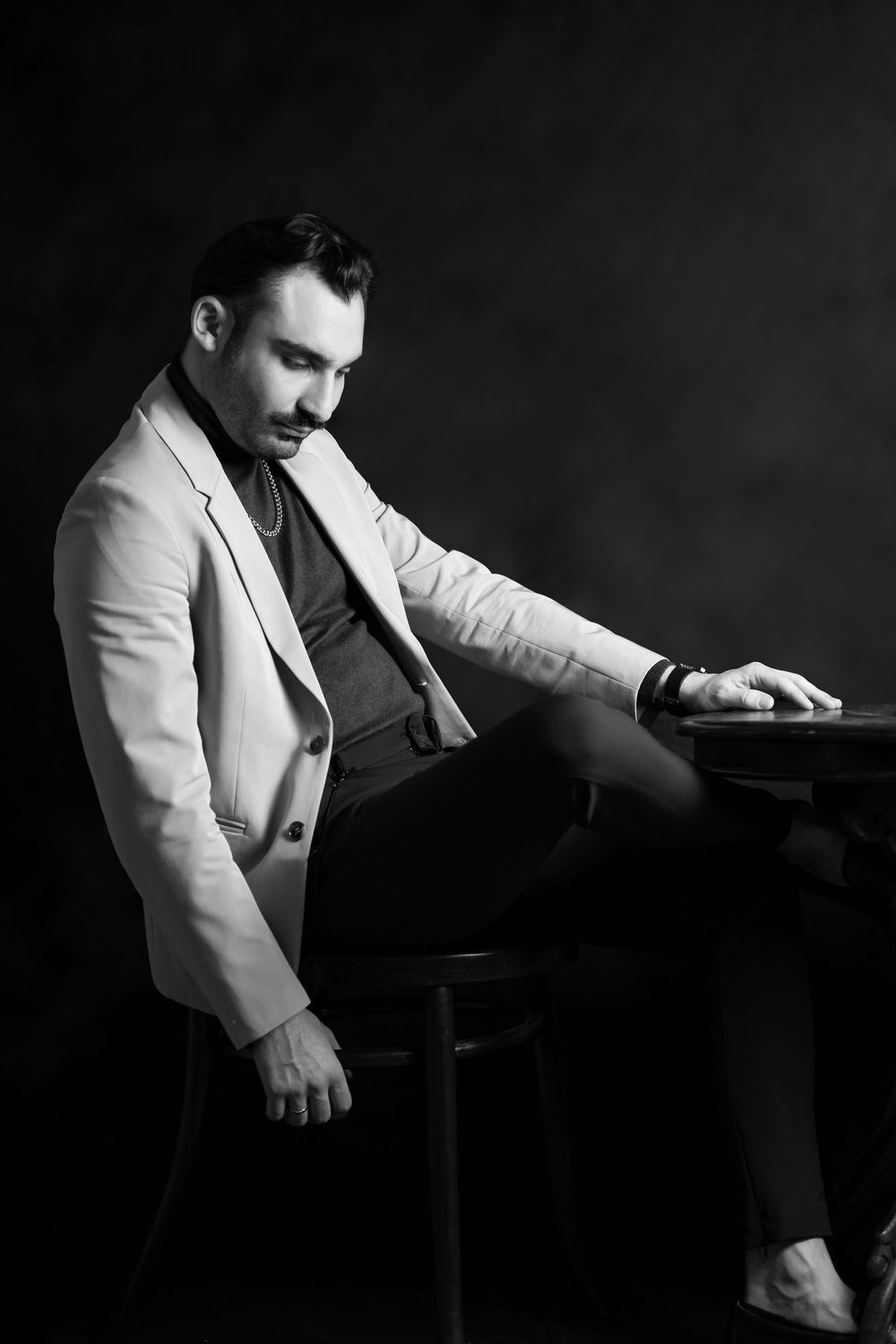 Black and white photograph of someone in a white blazer leaning over a piano keyboard in a dramatic pose.