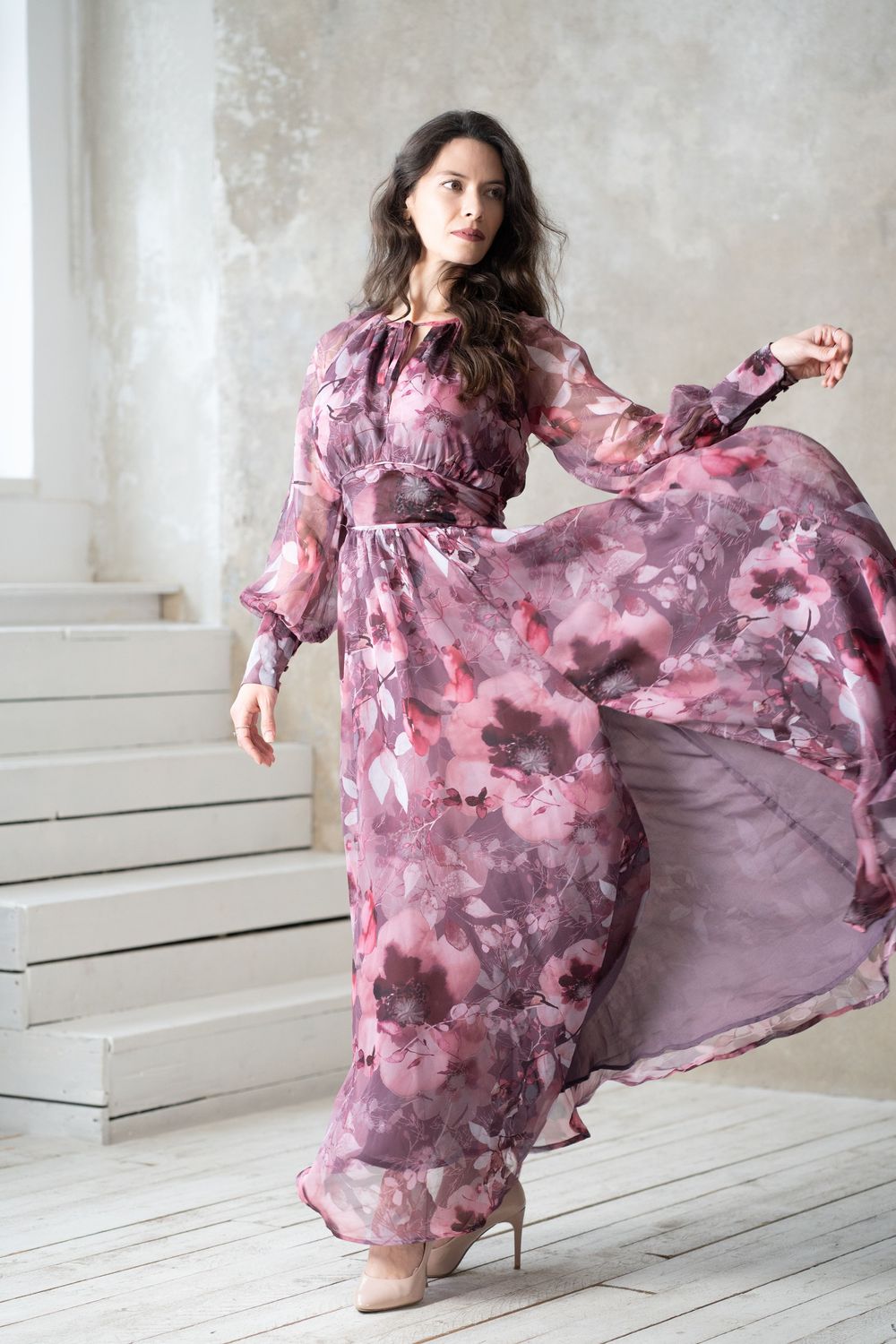Flowing watercolor-style pink and mauve floral dress in motion against white studio walls in series of dynamic poses.