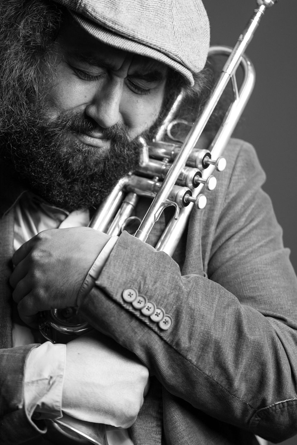 A montage of black and white photos showing close-up shots of someone playing a trumpet in dramatic lighting.