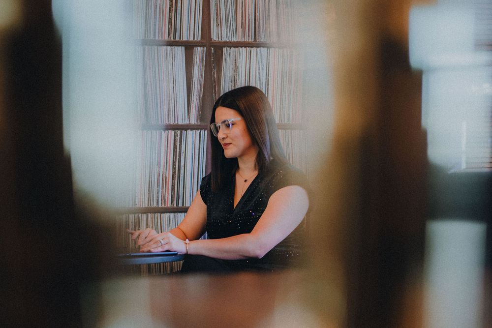 Someone sits at a desk working on a laptop computer in a moody, dimly lit office space.