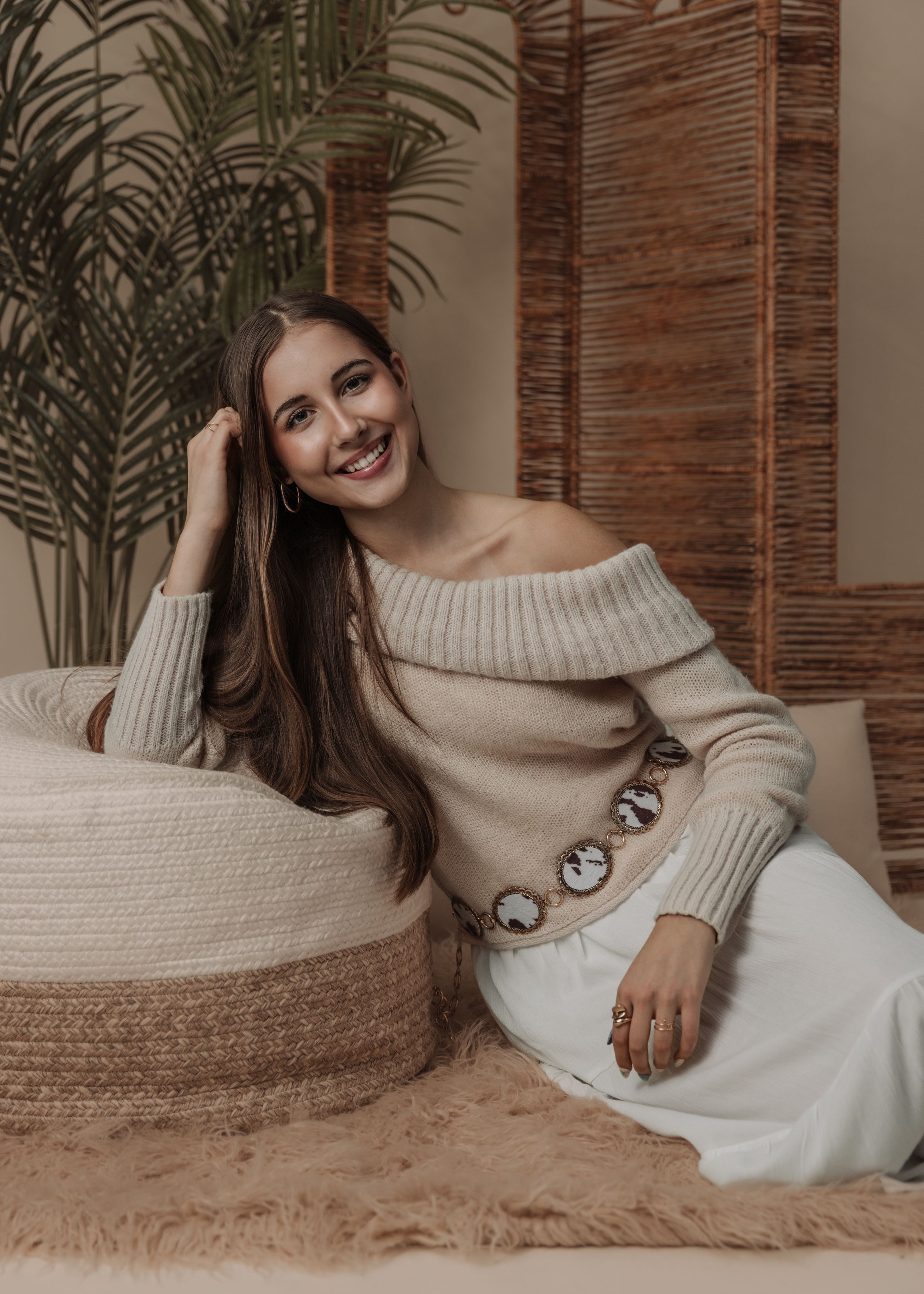 Cozy indoor portrait series with off-shoulder cream sweater and decorative buttons on plush carpet.