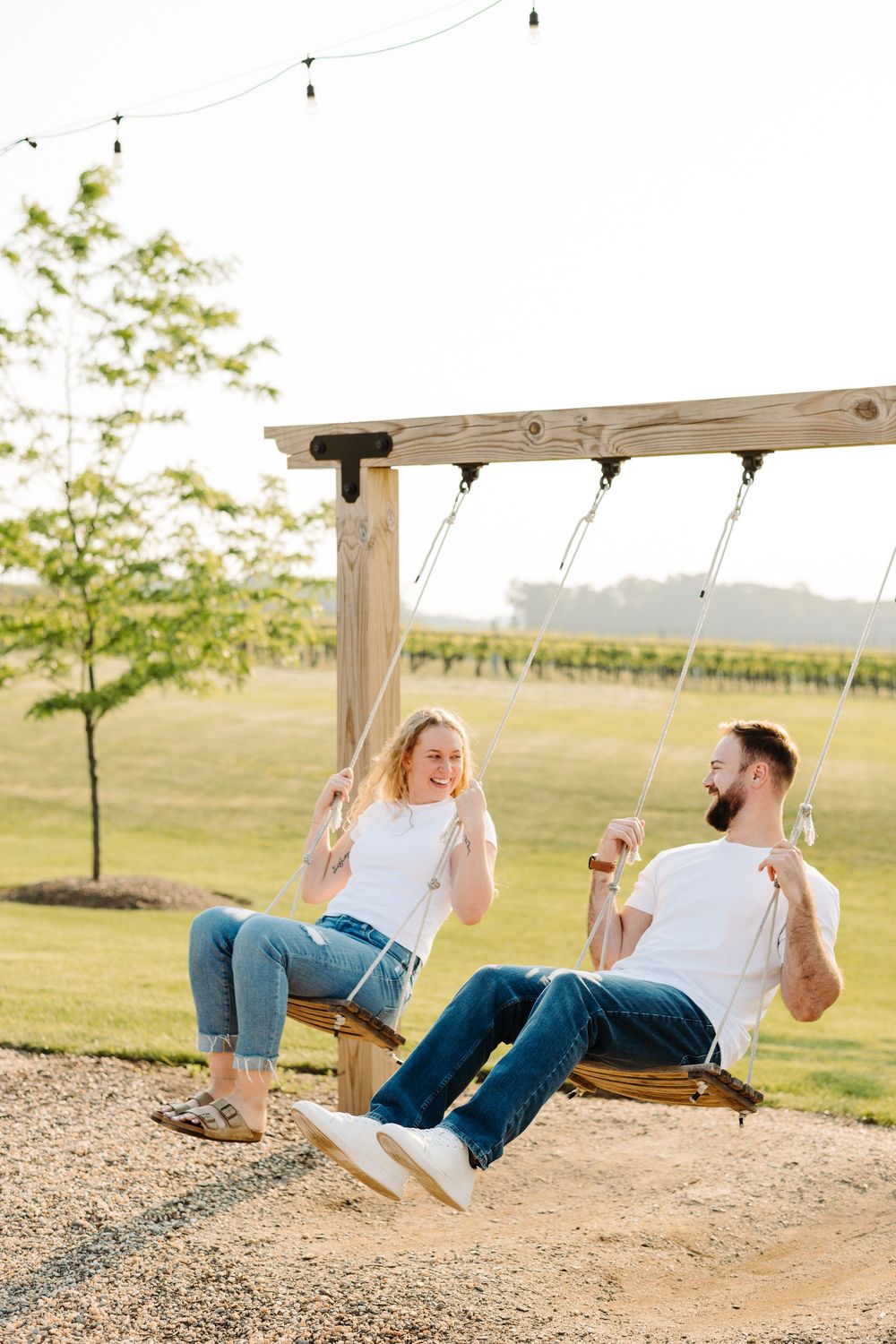 Playful sequence showing couple swinging together and falling back on a wooden swing in a sunny outdoor setting.