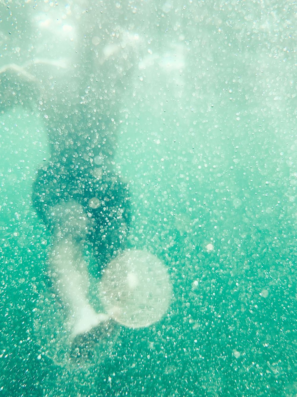 Ethereal turquoise underwater scene with sparkling bubbles and light rays.