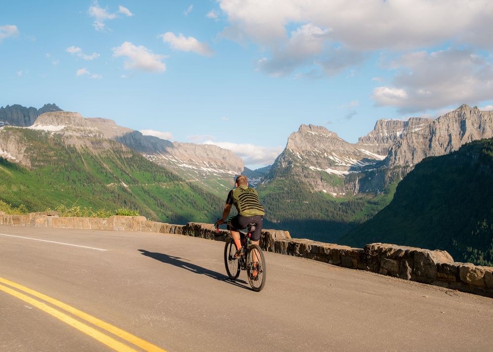 Mountain landscape with cyclists riding along scenic mountain road during summer day.