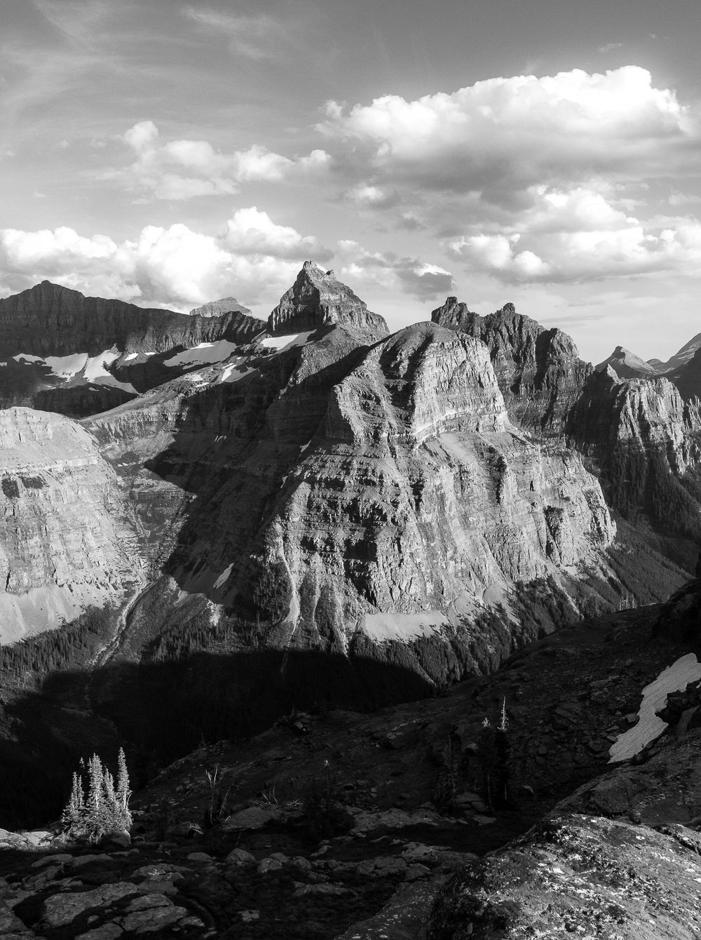 Dramatic black and white mountain landscape with jagged peaks and fluffy clouds in the sky.