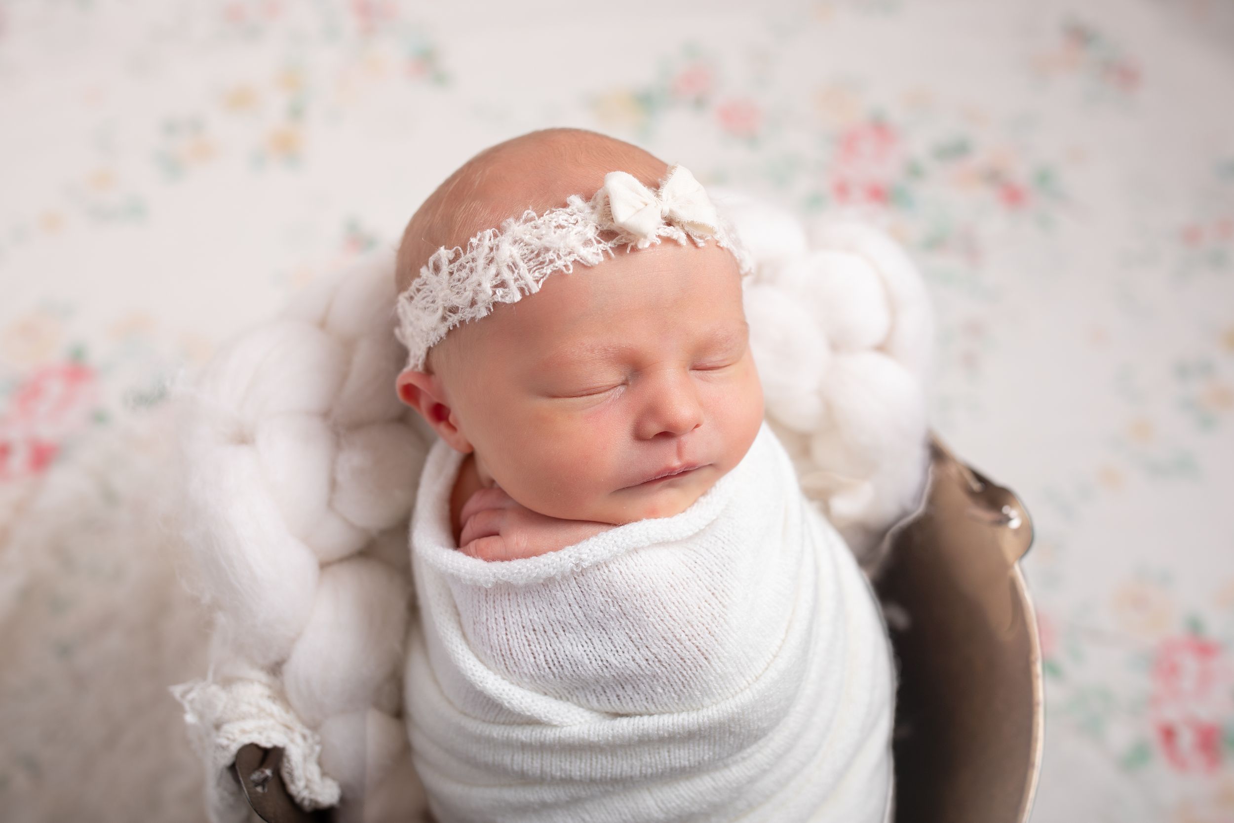 Newborn baby sleeping peacefully on floral patterned fabric.