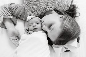 Black and white portrait of mother and baby lying together.