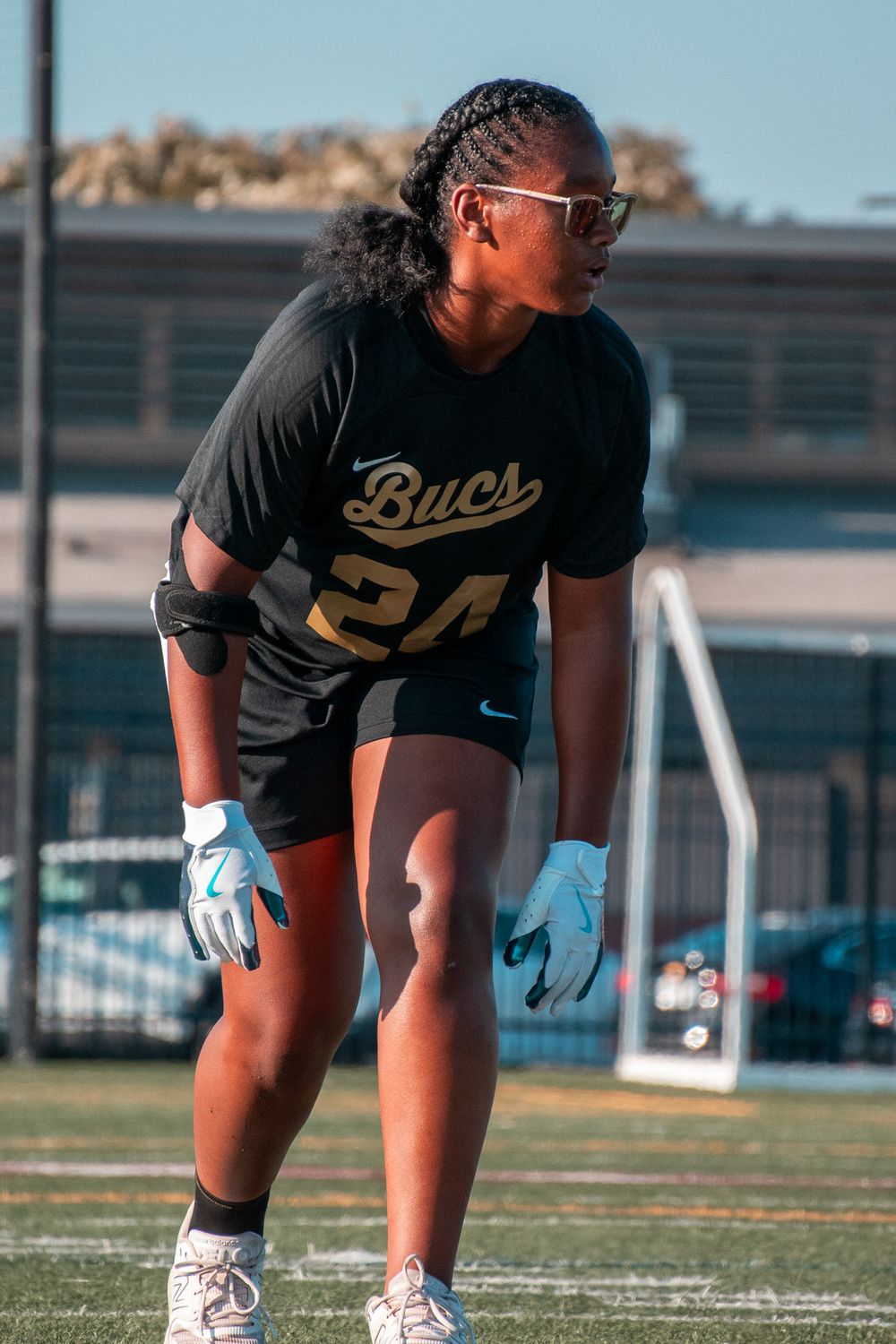 Player in black 'Bucs' jersey with number 24 stands ready on sports field.