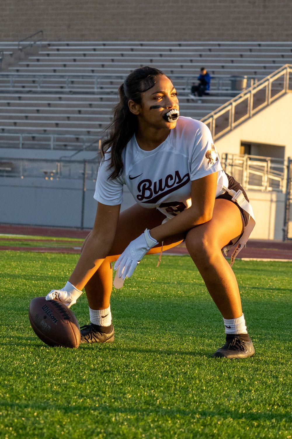 Soccer player in white jersey stretches on the grass field during practice.