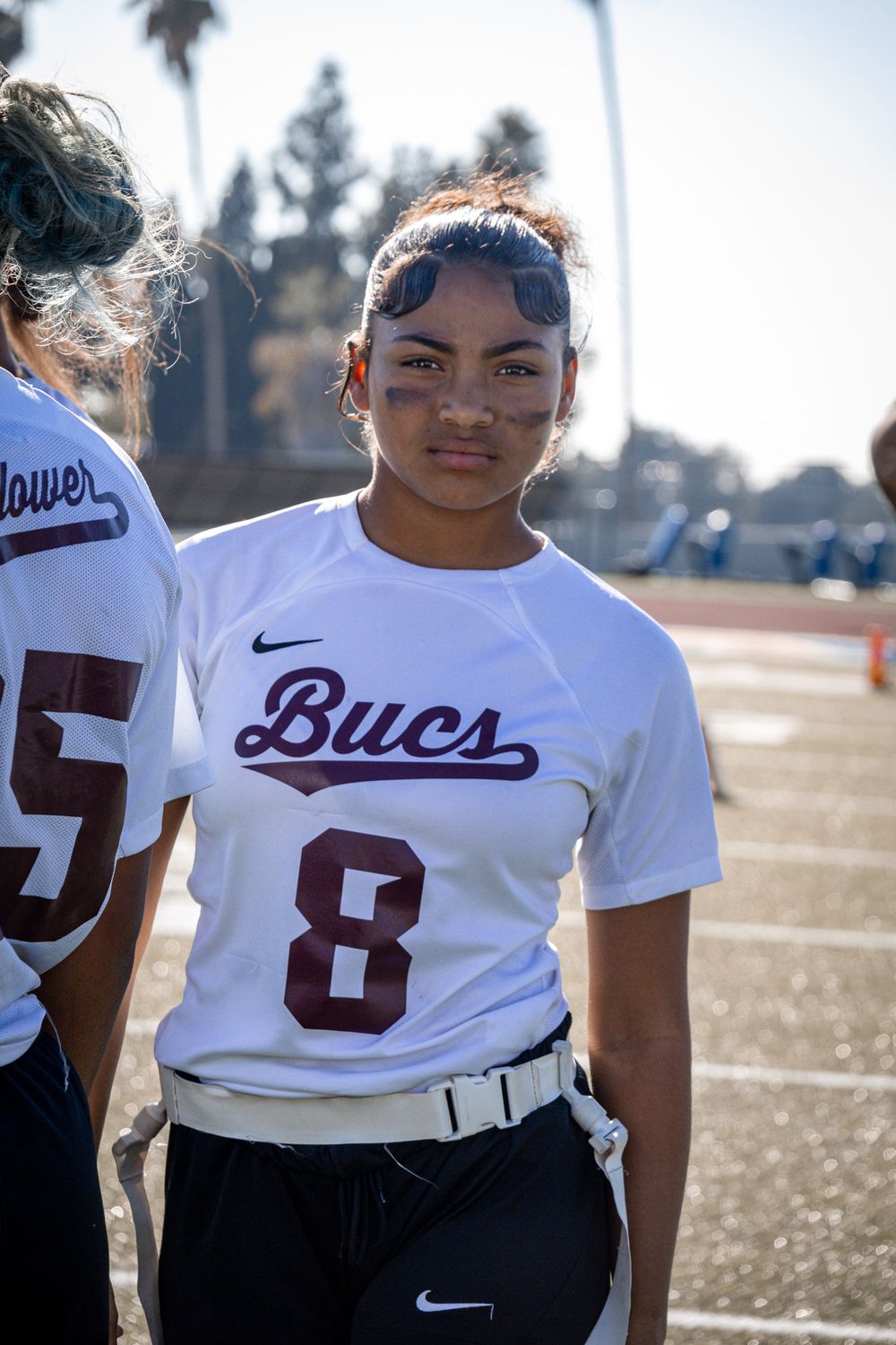 An athlete in a white Bucs uniform with number 8 stands on a sunny sports field.