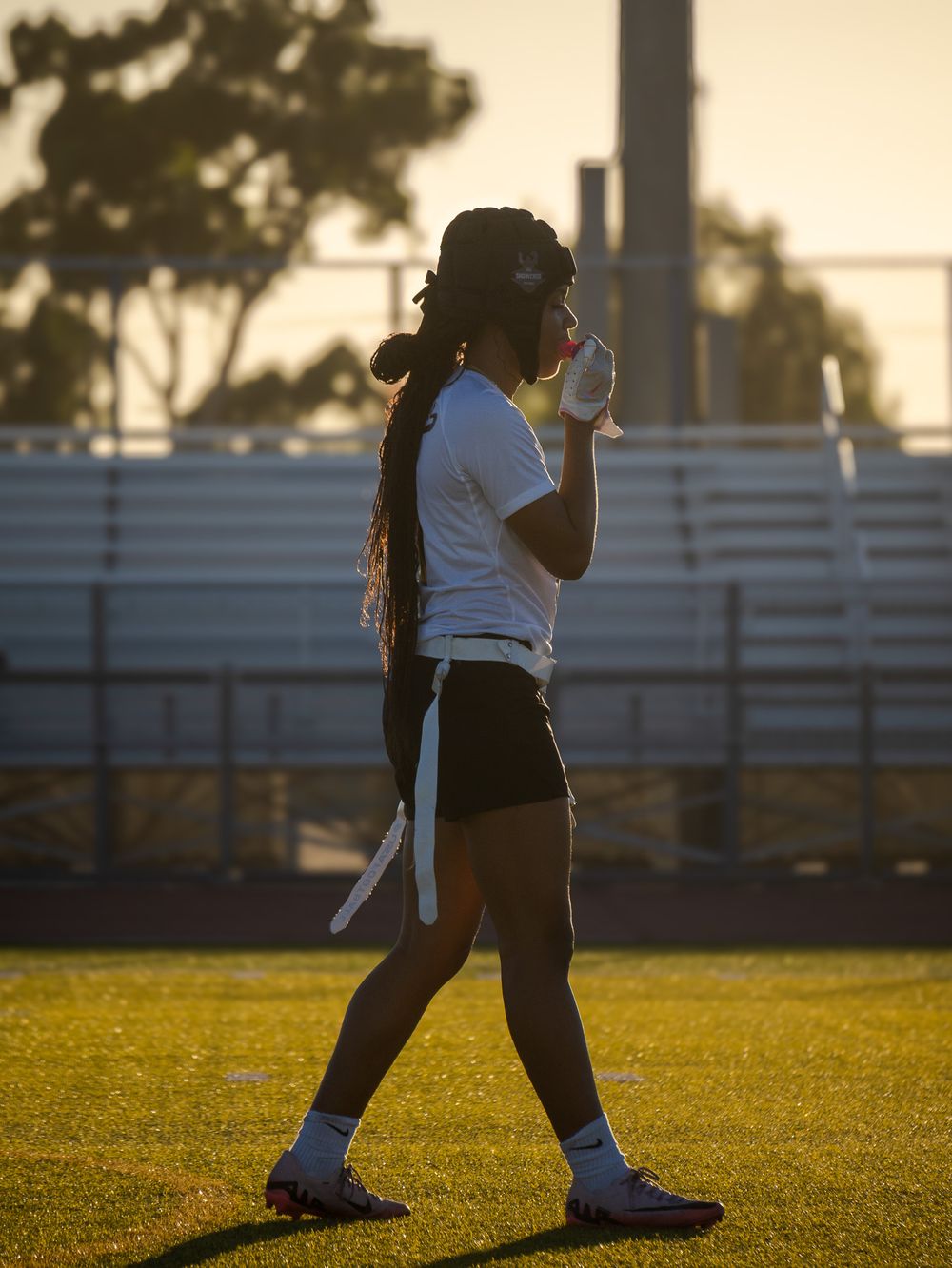 Silhouetted player in sports uniform gestures on field during sunset.