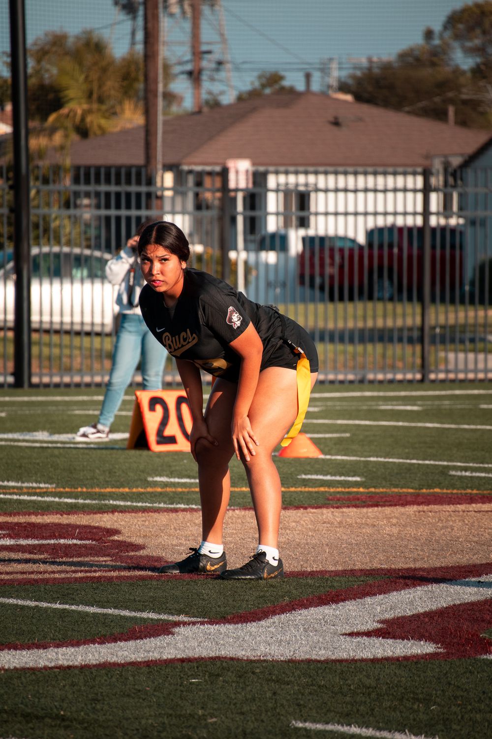 An athlete in uniform crouches in ready position on an athletic field.
