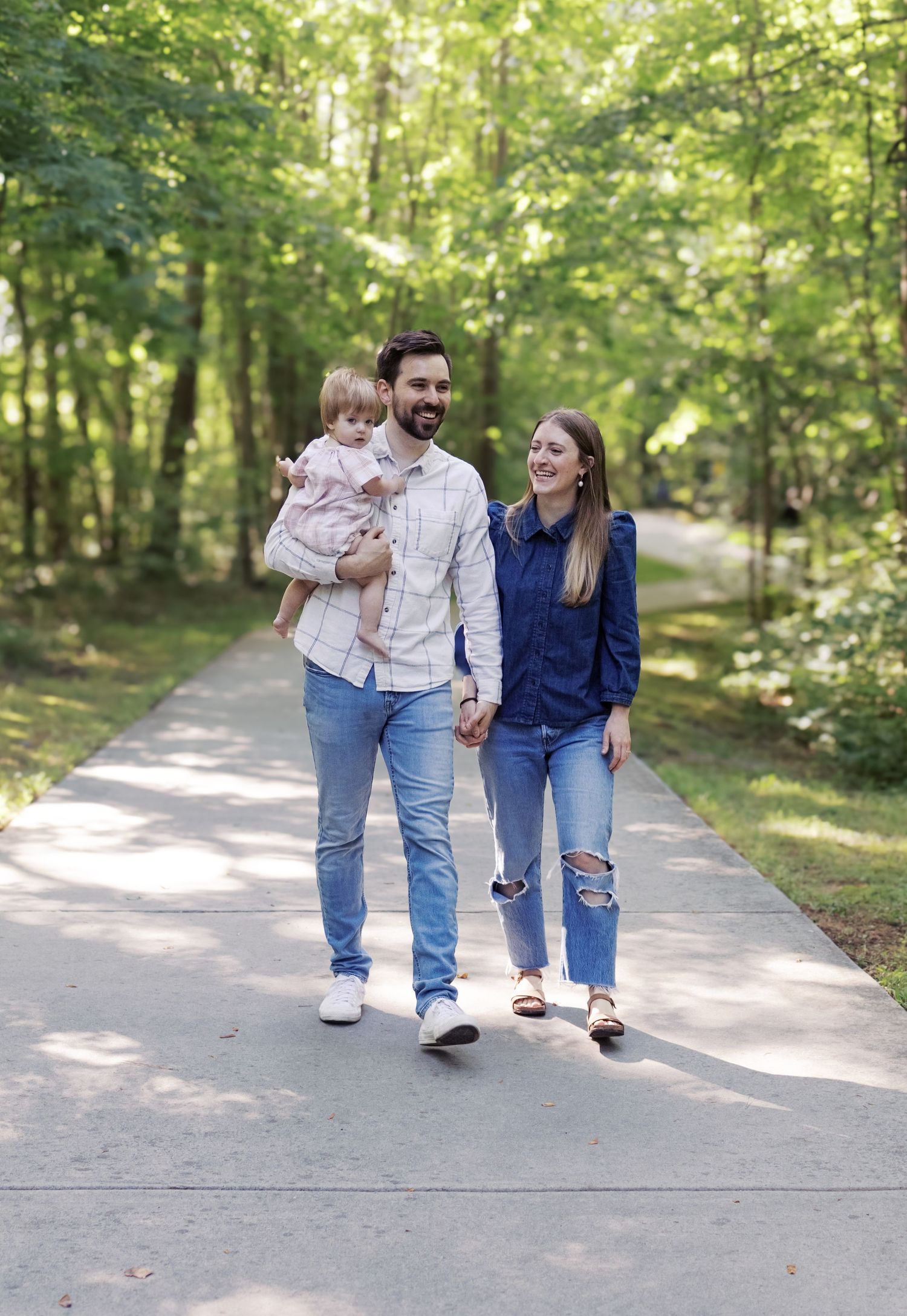 Family taking a stroll together on a sunny path through green woods.