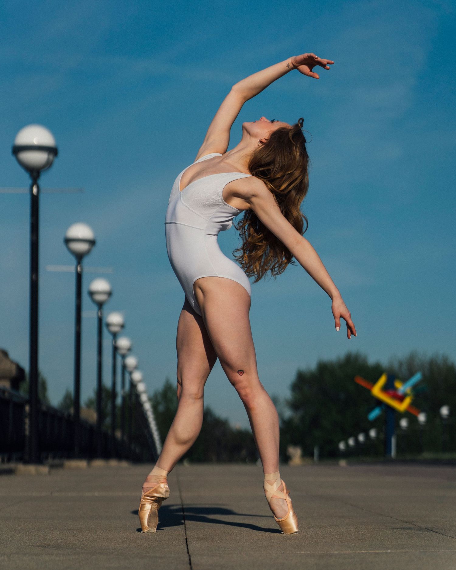 Petite ballerina from Indy Ballet en pointe at white river state park in the back ground in white leotard from indy dance photographer