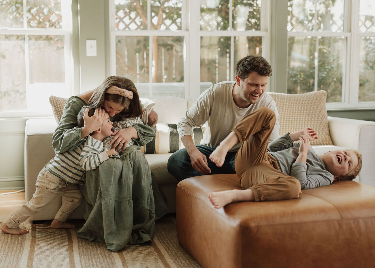 Intimate couple snuggling and relaxing together on a brown leather couch in a bright, modern living room.