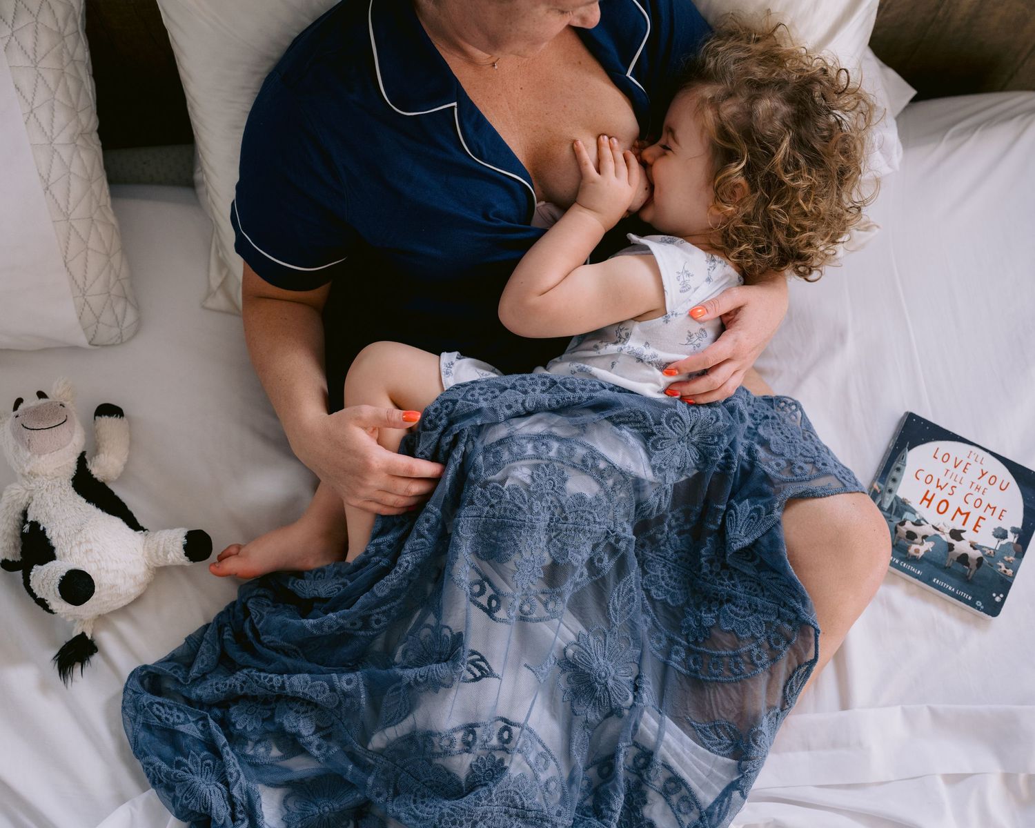 A close-up photo of a mother cradling her baby on a floral patterned blanket during lifestyle family photo session in Huntington Beach.