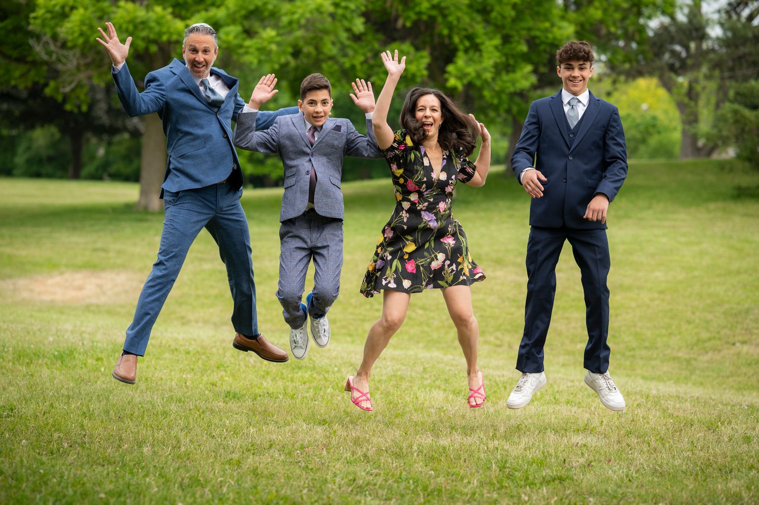 Happy family jumping in the air together in a park in Toronto, captured in natural light during a Bar Mitzvah photo session.