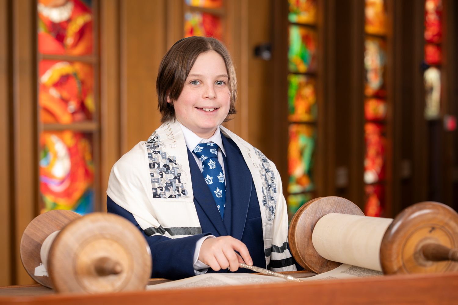 Traditional portrait of a Bar Mitzvah boy holding and reading the Torah.