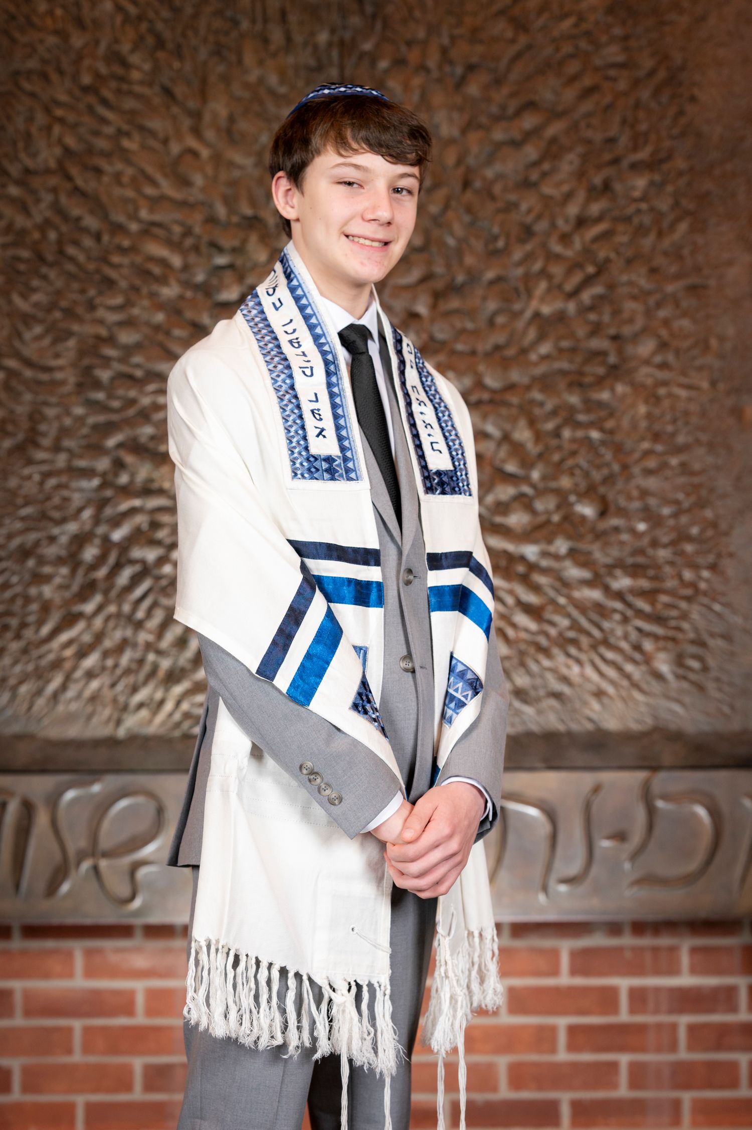Portrait of a Bar Mitzvah boy standing in front of the Ark at Temple Emanu-El.