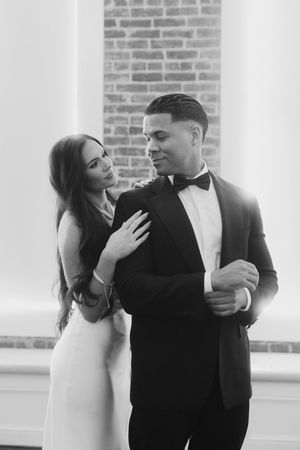 Romantic couple in formal wear sharing intimate moments in a bright studio with brick wall details.