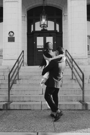 Series of playful poses on stone steps of a grand building entrance in black and white photography.