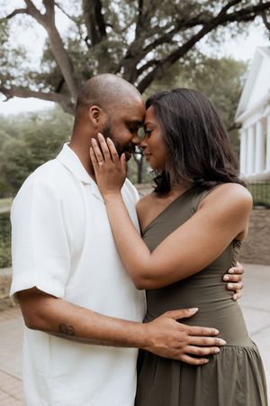 A tender moment shared between two people in formal attire standing close together in a garden setting.