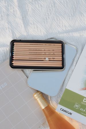 Several wooden pencils arranged neatly in a black case against a light blue background.