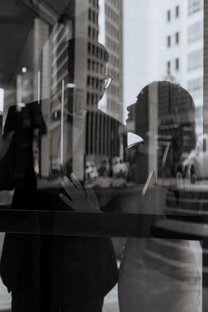 A black and white photo sequence showing silhouettes through reflective windows in an urban setting.