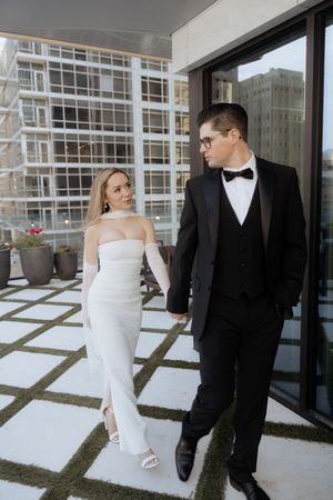 Modern rooftop wedding photoshoot with couple against urban backdrop.