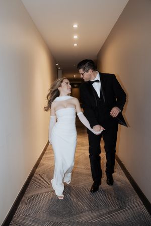 Candid moment of couple walking and laughing together in modern hotel hallway.