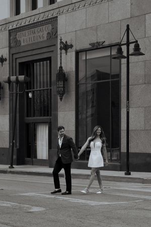 Couple holding hands crossing a street in black and white photo outside the Lone Star Gas Co. Building.
