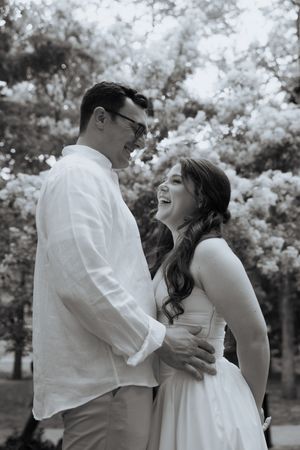 A joyful couple shares an intimate embrace outdoors surrounded by beautiful cherry blossoms in spring.